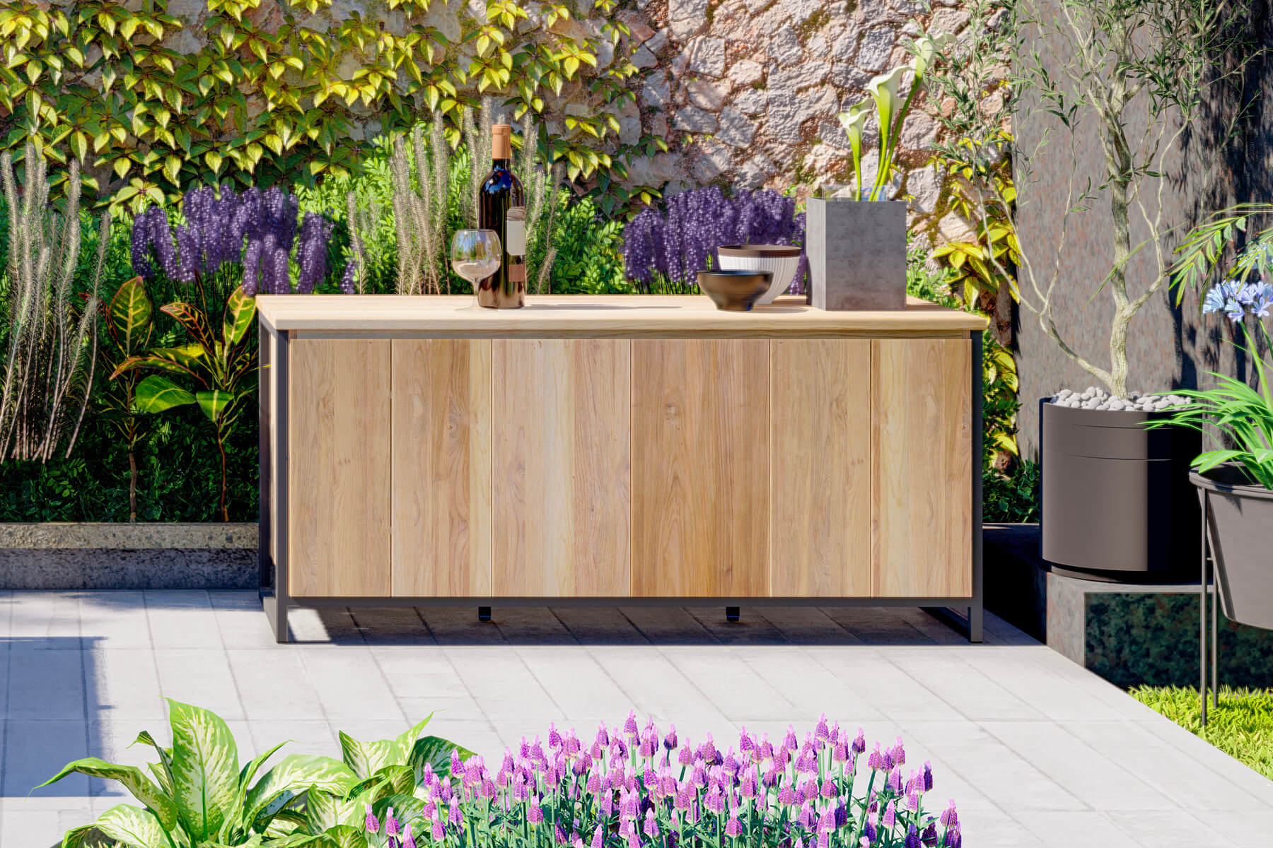 Outdoor-K&uuml;chenmodul aus Teak mit heller Arbeitsplatte, Sp&uuml;le und Schrankt&uuml;ren vor einer berankten Natursteinmauer